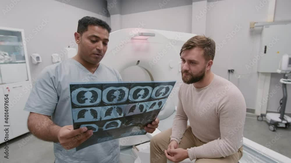 Handheld tracking of Arab male radiologist in scrubs holding xray of
