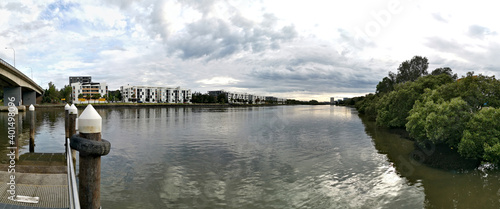 Beautiful panoramic view of a river with reflections of bridge, modern apartment buildings, cloudy sky and trees on water, Parramatta river, Wilson Park, Sydney, New South Wales, Australia
 photo