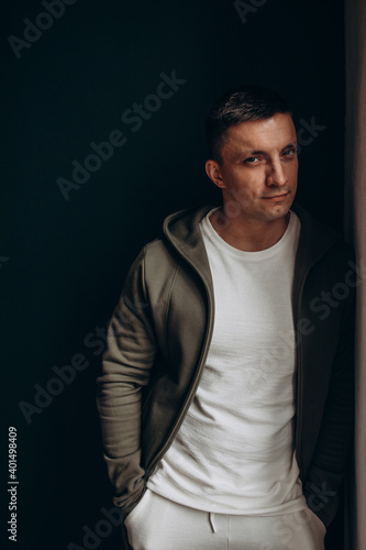 Portrait of a guy. Young man in a sweatshirt with a hood. Black background. © dimadasha