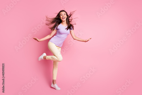 Full body photo of childish funky girl raise hands knee flowing hair dressed casual isolated on pink color background