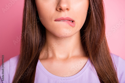 Close-up photo portrait of woman biting lower lip isolated on pastel pink colored background photo