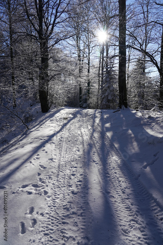 Mountain path covered with snow in sunny winter day at sun background