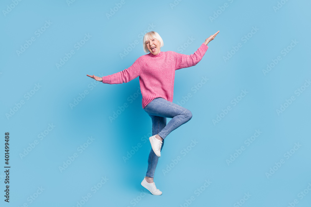 Photo portrait full body view of happy old lady dancing standing on one leg isolated on pastel blue colored background - obrazy, fototapety, plakaty 