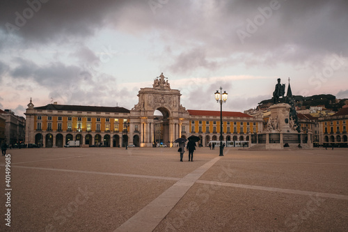 Couple walking in Comercio Square at sunset, Lisbon, Portugal