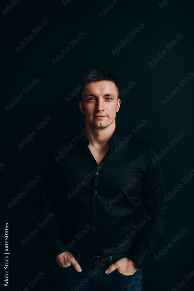 Portrait of a successful businessman. The guy in the black shirt. Black background.