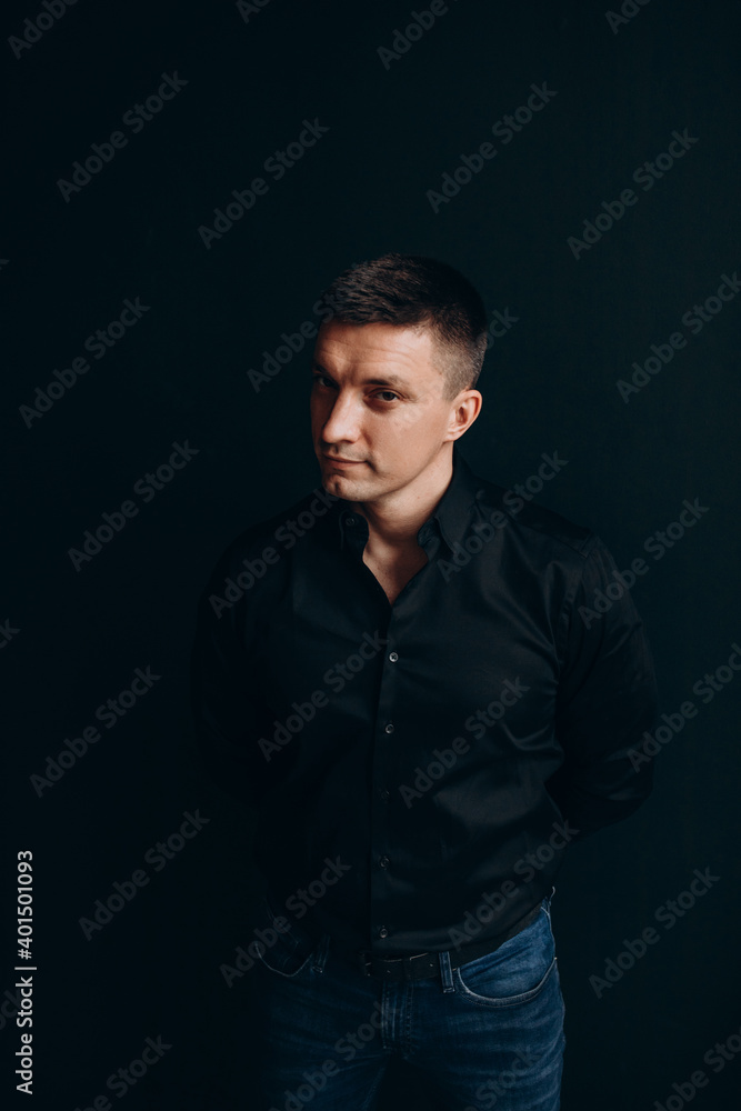 Portrait of a successful businessman. The guy in the black shirt. Black background.