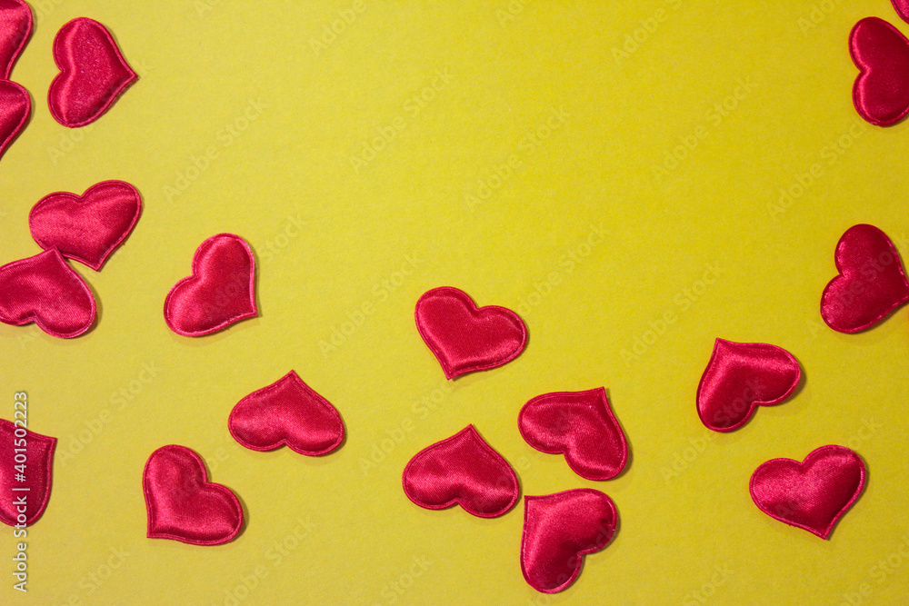 Small red hearts that are scattered on a yellow background.