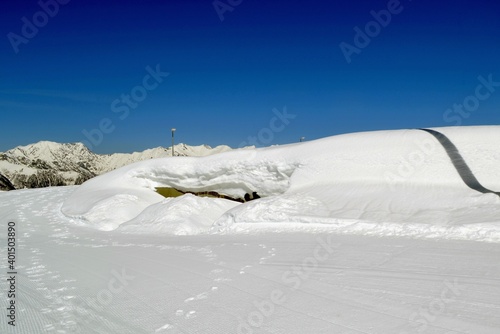 High snowdrifts against the background of fir trees and blue sky.