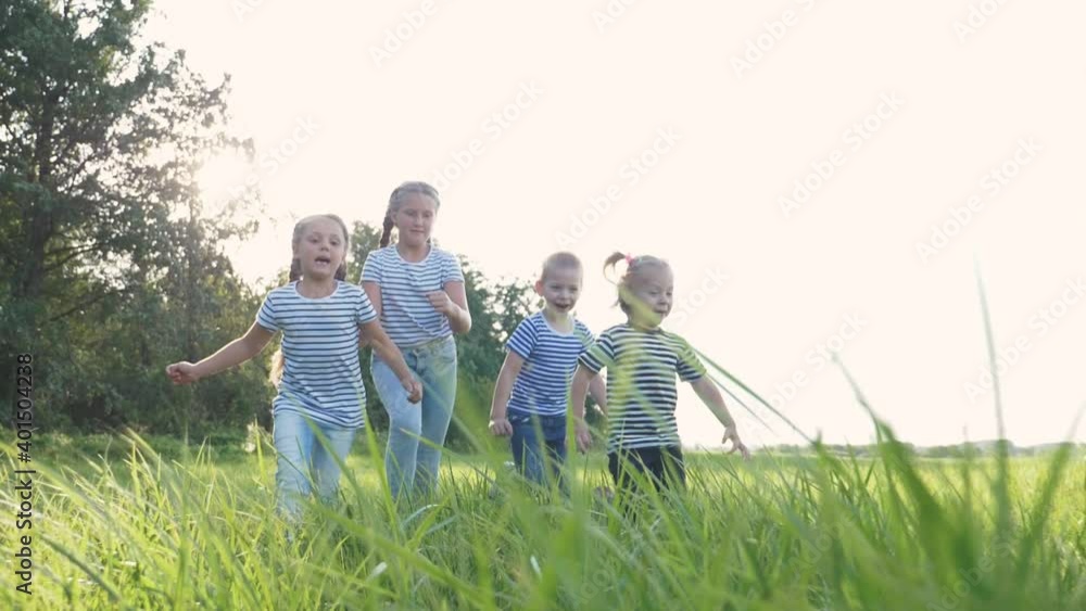 Happy family of children has fun in the park. Children flee the green lawn in droves. Kids play fun at sunset in the park. Teamwork, playing girls and a boy. Happy family of children has fun in the park. Children flee the green lawn in droves. Kids play fun at sunset in the park. Teamwork, playing girls and a boy.