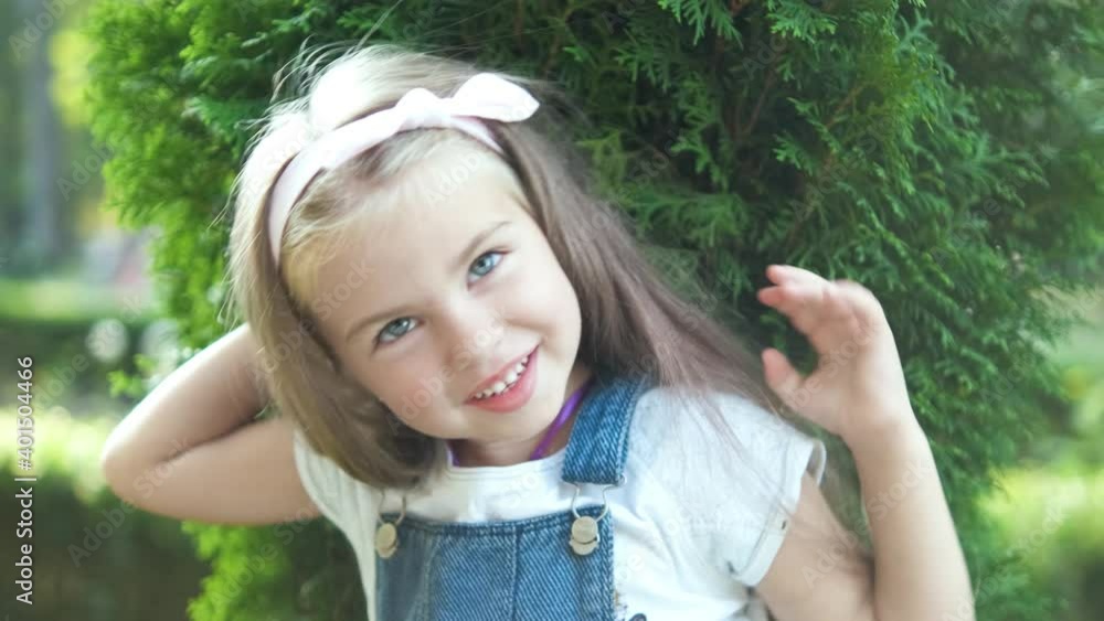 Portrait of pretty child girl standing outdoors in summer park waving her hand. Portrait of pretty child girl standing outdoors in summer park waving her hand.