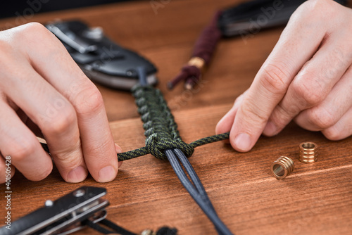 Close-up on hands making a paracord cobra lanyard for pocket knife photo