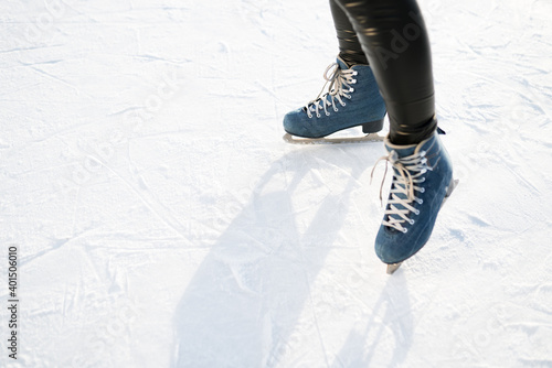 Photo of blue skates with white lacing against the background of sun glare in winter