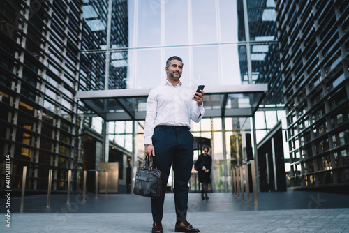 Photos Mature businessman in formal wear standing at urbanity with company building on