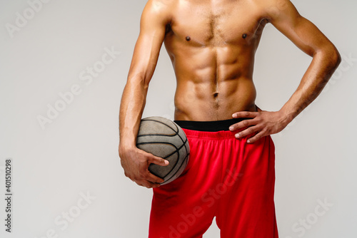 Muscular african american sportsman playing basketball shitless over light grey background photo