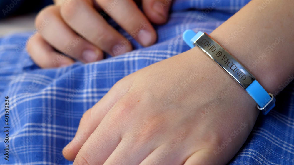 Obraz premium Child hand with vaccined bracelet or label after injection in hospital. Unrecognizable female person after quarantine. Prevention precaution to preserve health. Safety and coronavirus pandemic concept