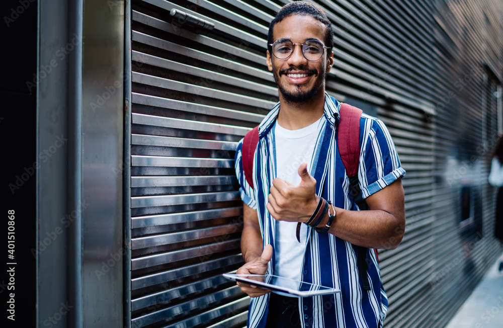 Half length portrait of smiling dark skinned man satisfied with 4G connection for browsing via touchpad on urban settings,smiling african american hipster guy gesturing showing thumb up holding tablet Half length portrait of smiling dark skinned man satisfied with 4G connection for browsing via touchpad on urban settings,smiling african american hipster guy gesturing showing thumb up holding tablet