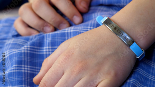 Child hand with vaccined bracelet or label after injection in hospital. Unrecognizable female person after quarantine. Prevention precaution to preserve health. Safety and coronavirus pandemic concept