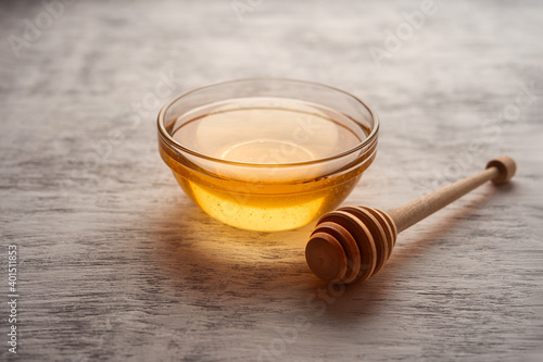 Fresh acacia honey in a glass bowl near the honey Mace