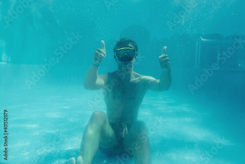 Man swimming underwater in the pool at daytime. Having fun
