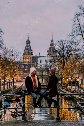 couple on city trip Amsterdam Netherlands canals with Christmas lights during December, canal historical center of Amsterdam at night. Europe