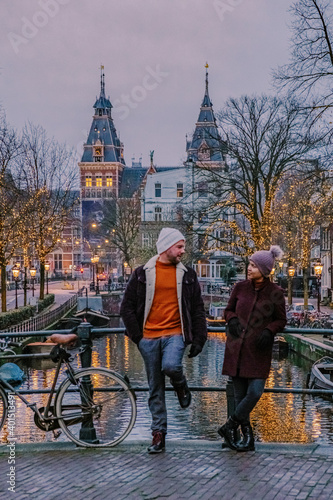 Photography couple on city trip Amsterdam Netherlands canals with Christmas lights during December, canal historical center of Amsterdam at night