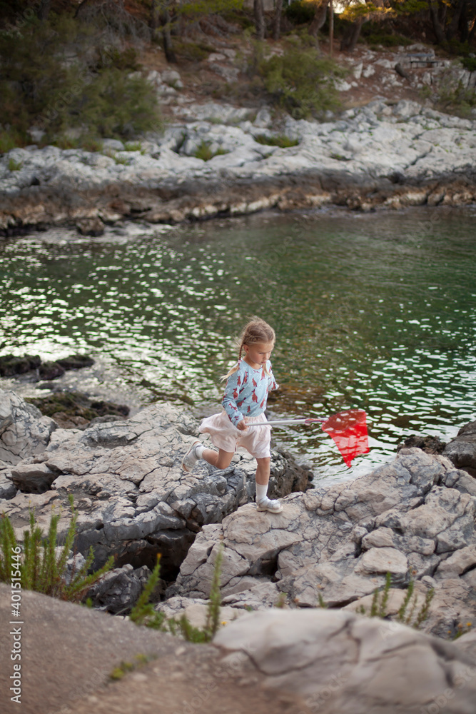Cute baby-girl running on the cliff near the sea with a red net. Cute baby-girl running on the cliff near the sea with a red net.