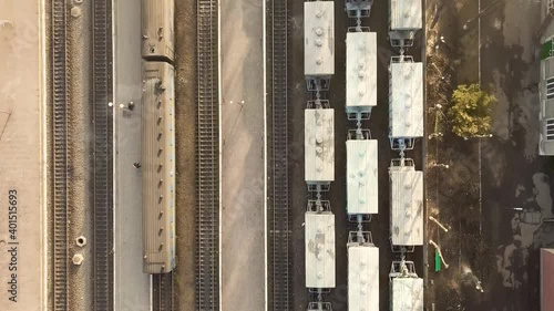 Top down aerial view of many cargo train cars on railway tracks.