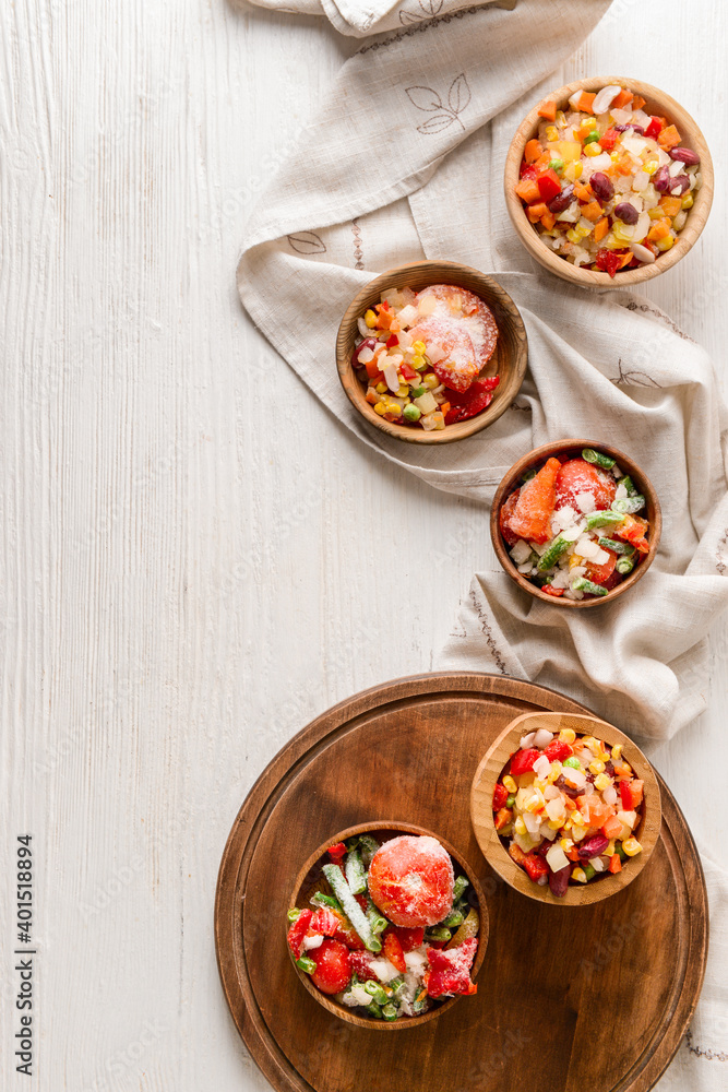 Frozen vegetables in bowls on light background Frozen vegetables in bowls on light background