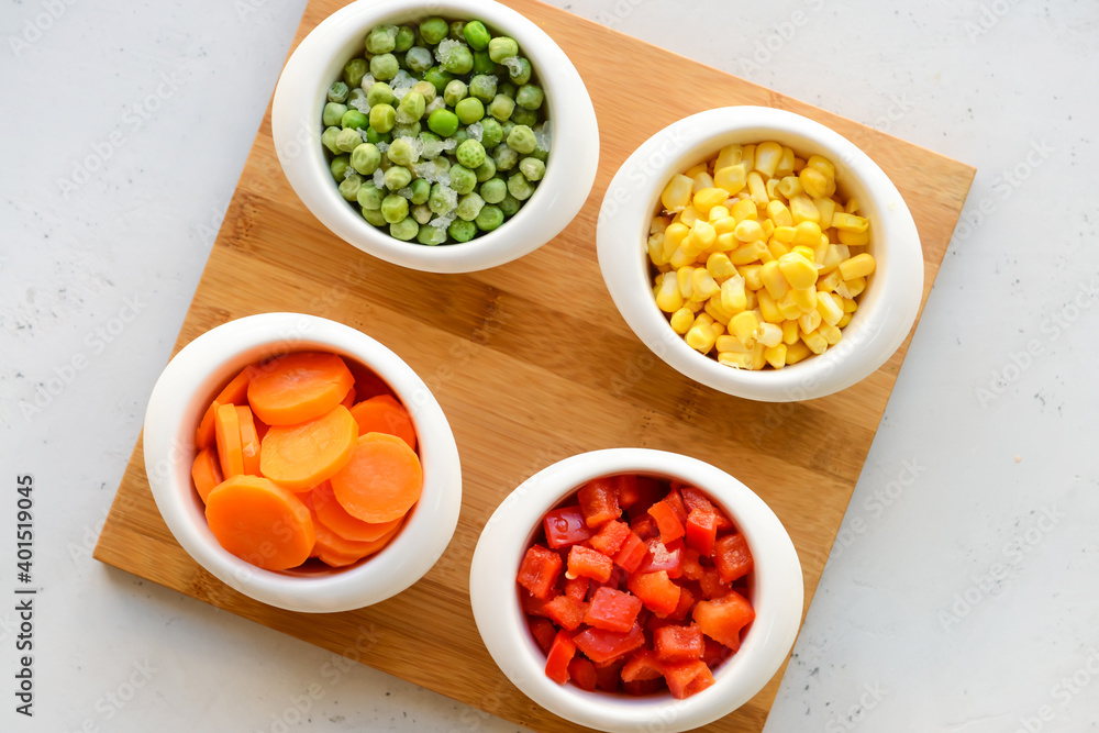 Frozen vegetables in bowls on light background Frozen vegetables in bowls on light background