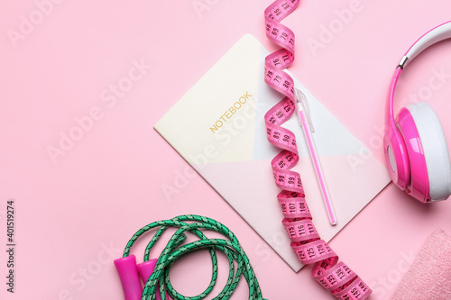 Measuring tape and notebook on color background