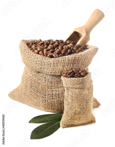 Bags with coffee beans and scoop on white background