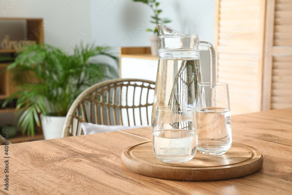 Jug and glasses with water on table in stylish dining room Jug and glasses with water on table in stylish dining room