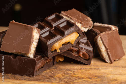 Pieces of chocolate bar filled with chocolate and vanilla cream on wooden plate