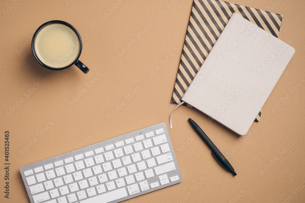 Modern workspace with keyboard, notebooks, pen, cup of coffee on brown background. Top view, flat lay office desk table. Modern workspace with keyboard, notebooks, pen, cup of coffee on brown background. Top view, flat lay office desk table.