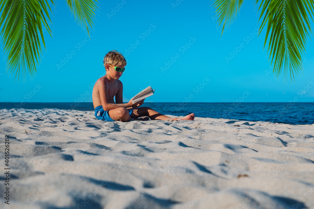 boy reading book at sand beach, kid learning on vacation