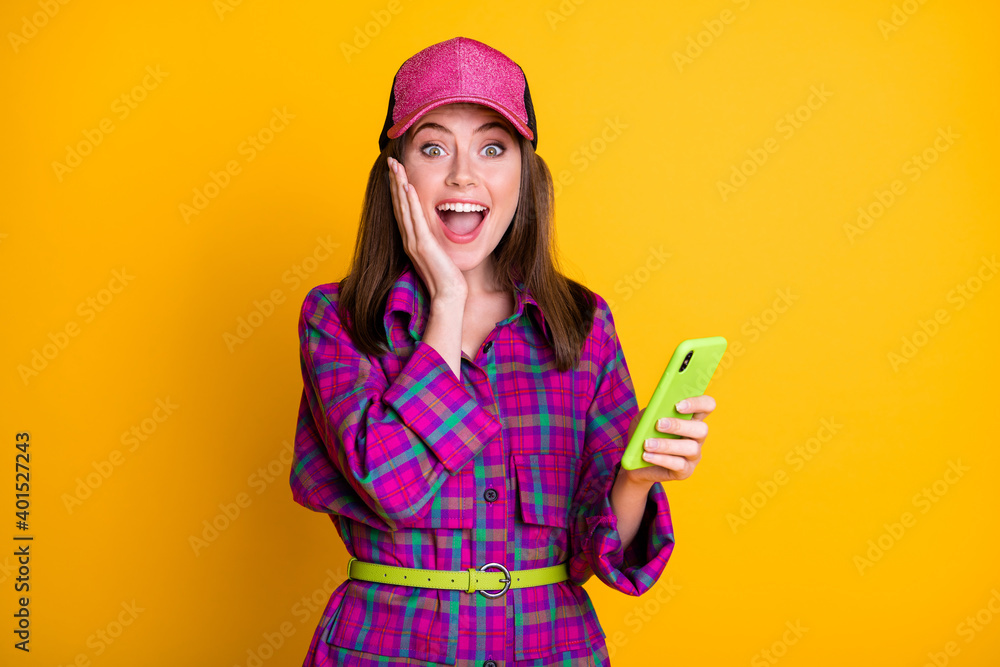 Photo of astonished person arm on cheek open mouth magenta plaid clothing headwear isolated on yellow color background Photo of astonished person arm on cheek open mouth magenta plaid clothing headwear isolated on yellow color background