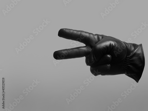 black leather glove shows two fingers gesture. isolated neutral background. copy space