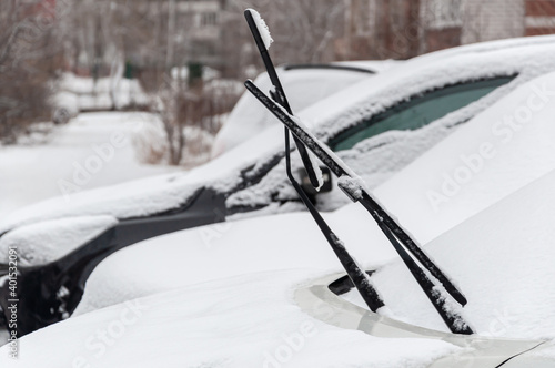 Parked snow-covered cars with raised wipers