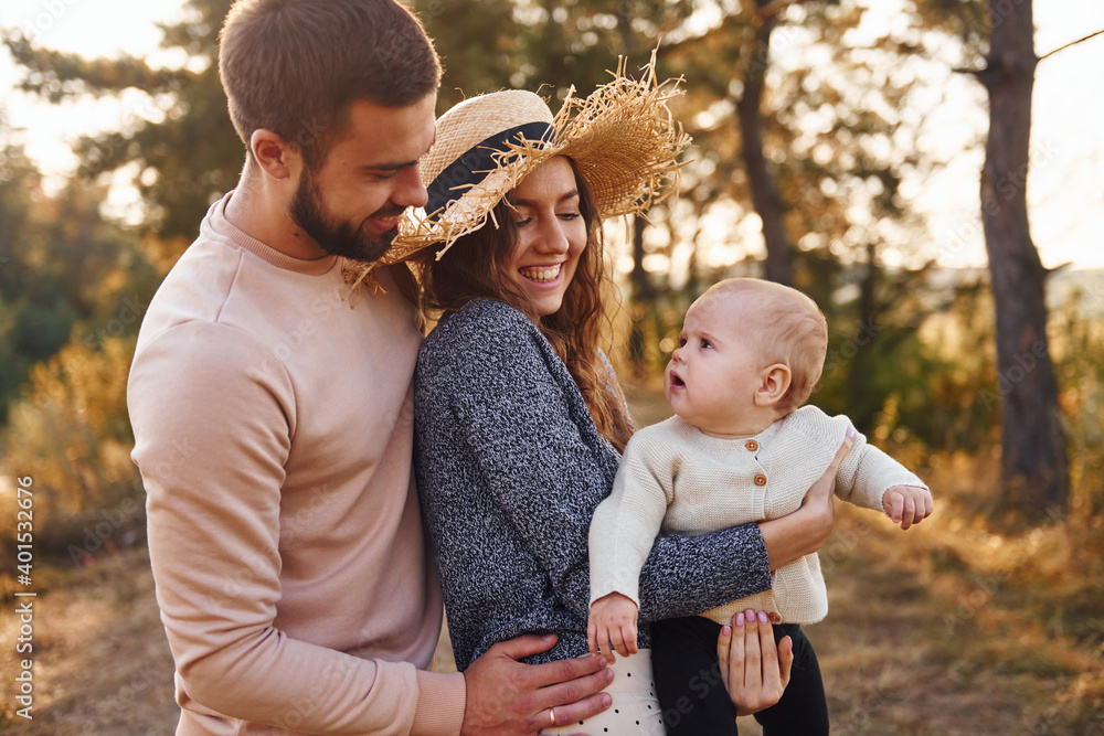 Obraz premium Happy family of mother, family and little baby rests outdoors. Beautiful sunny autumn nature