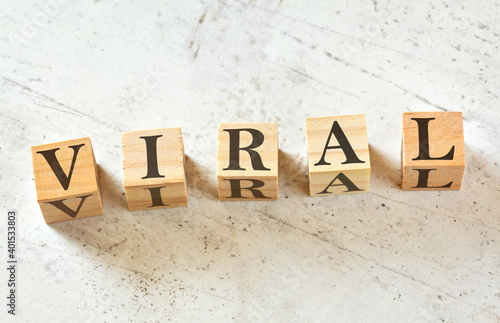 Five wooden cubes with word VIRAL on white stone like board, view from above