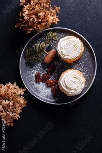 2 small and sweet tartlets with white cream on top and powder censer on a black table photo