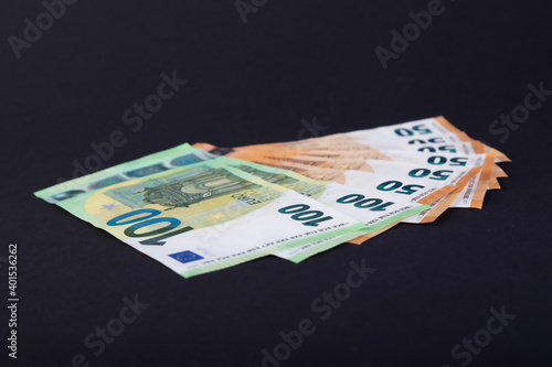 100 and 50 Euro bank notes in a row on black background
