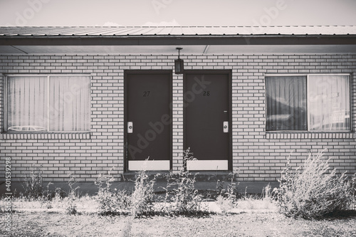 Old abandoned seedy motel, with overgrown weeds in the parking lot