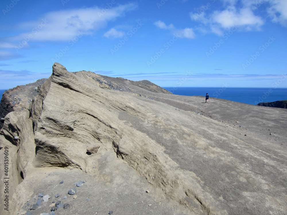 Woman hiking to one of the peaks at Capelinhos volcano, Faial, Azores.