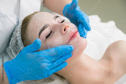 Cosmetologist is applying moisturizing cream on woman face after plasmalifting injections procedure, face closeup. PRP therapy in beauty clinic. Treatment of skin in cosmetology.