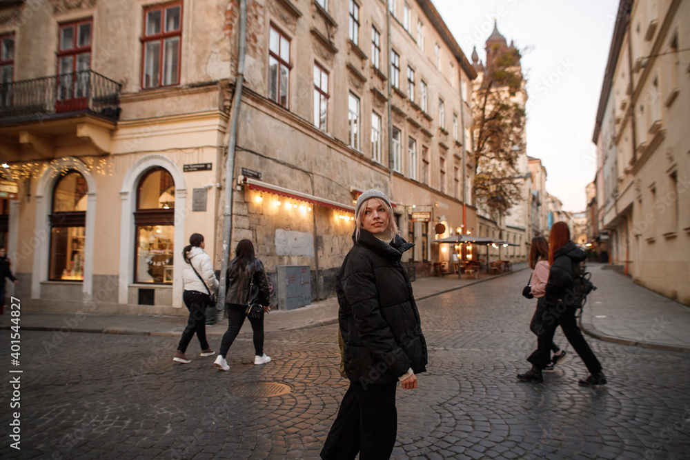 young woman walks in the evening old town