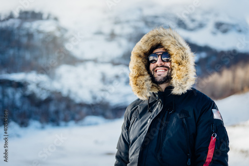 Happy male tourist smiling in nature on a mountain during an active holiday vacation.Hiker on a winter trek.Ski season, extreme snow sport adventure.