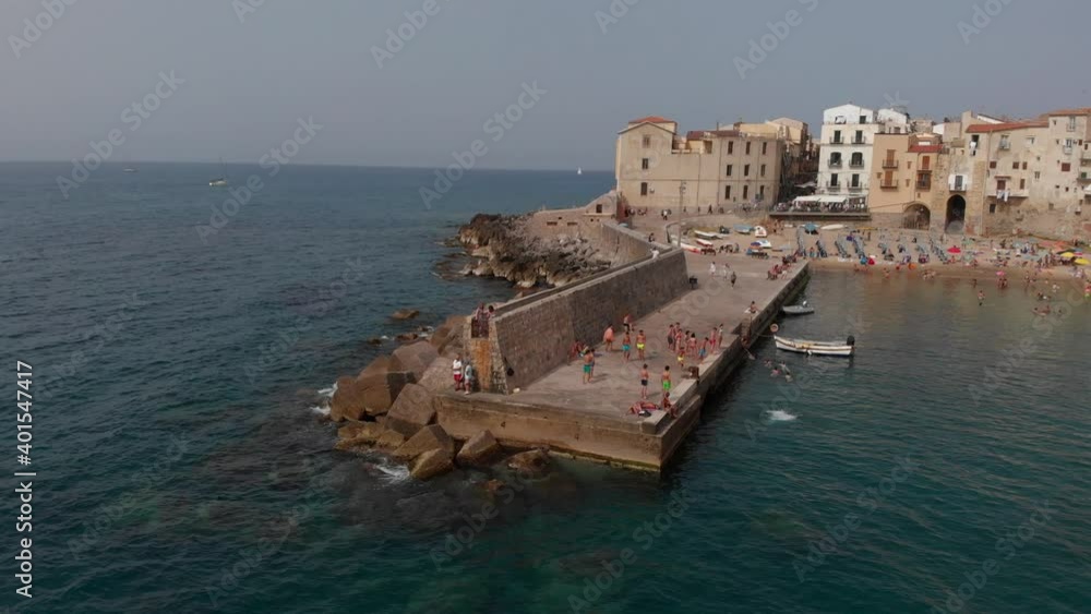 people dive into the water from the pier in Cefalu people dive into the water from the pier in Cefalu