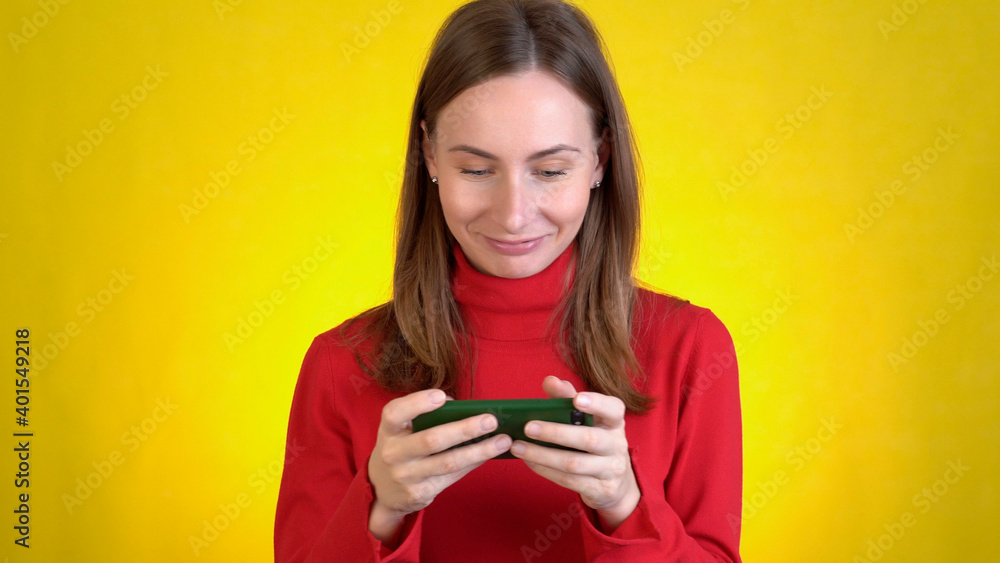 Gambling young woman play mobile cell phone hold gadget smartphone video pc games isolated on yellow background studio People lifestyle concept Gambling young woman play mobile cell phone hold gadget smartphone video pc games isolated on yellow background studio People lifestyle concept