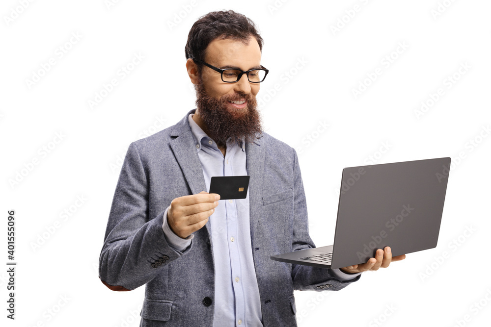 Bearded man with glasses holding a credit card and looking at a laptop computer Bearded man with glasses holding a credit card and looking at a laptop computer